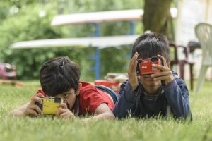 Mustafa, from Iraq, and Durica, from Serbia, play with action cameras in a playground within the barracks.